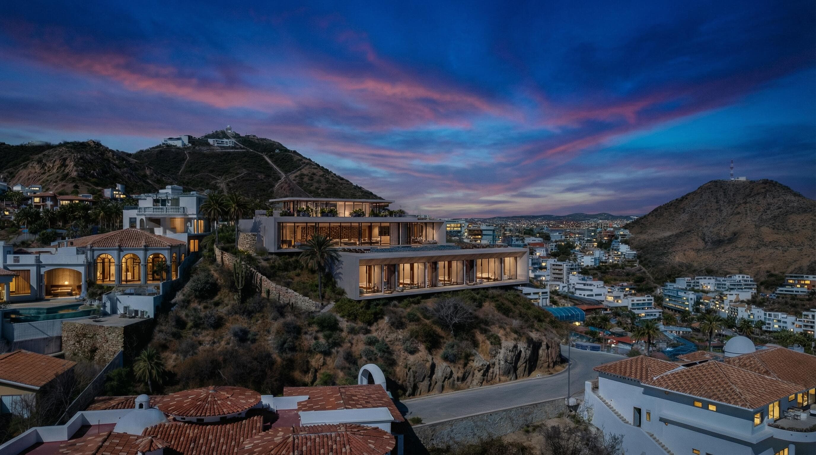 Villa del León at dusk on the Pedregal ridge under a streaked Cabo sunset
