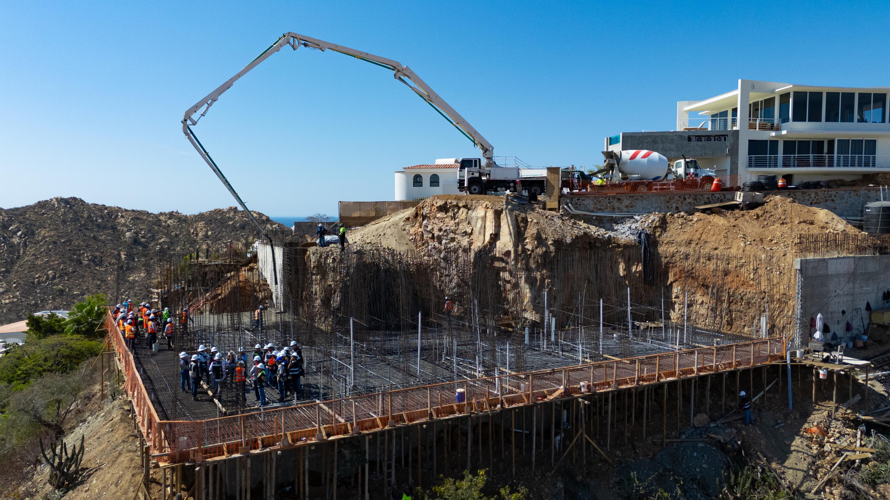 Rebar grid, crew, and concrete pump on the Villa del León slab in Pedregal, Cabo