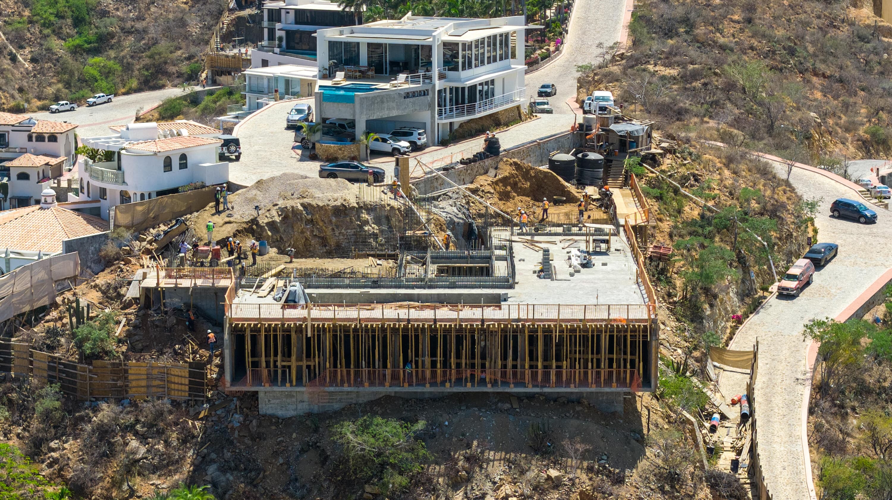 Villa del León cantilever formwork and workers on the steep Pedregal lot in Cabo