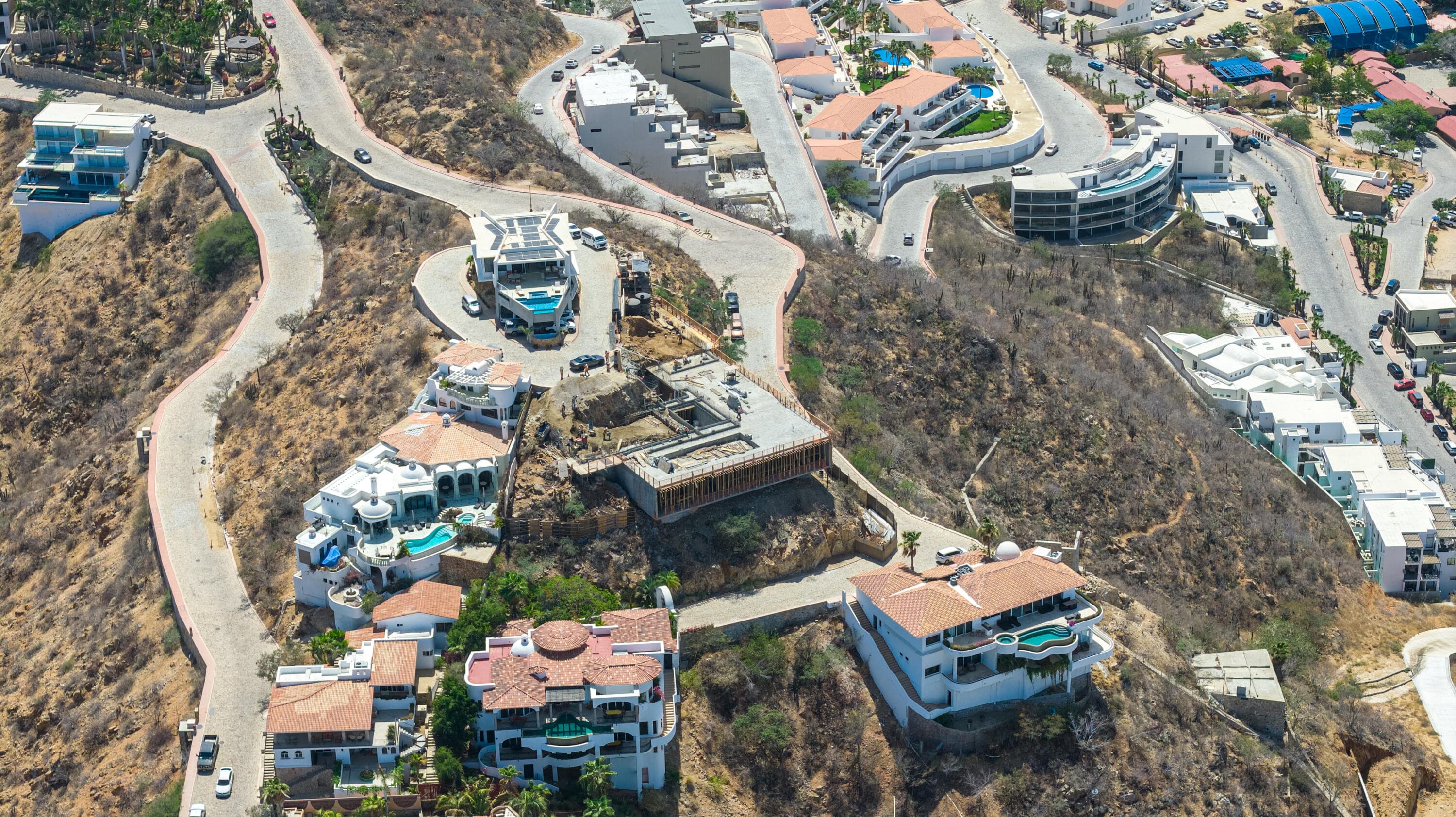 Wide aerial of the Pedregal hillside in Cabo San Lucas and the Villa del León build